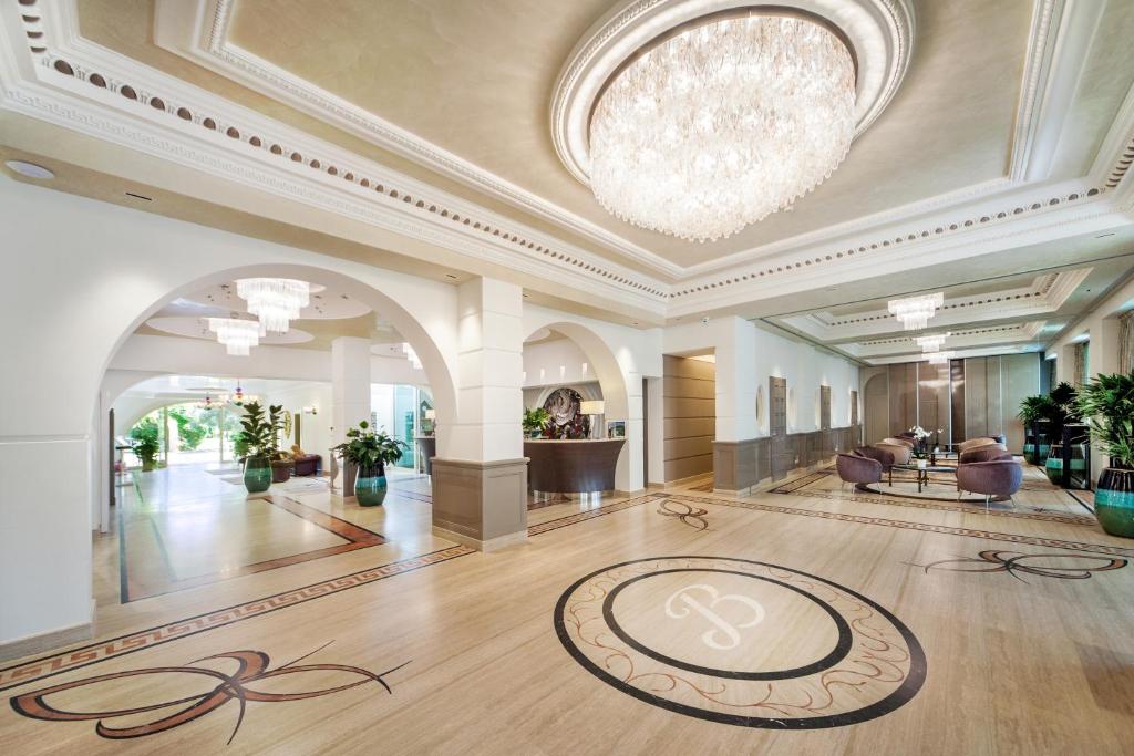 un grand hall avec un lustre et une grande salle dans l'établissement Hotel Aurelia, à Milano Marittima