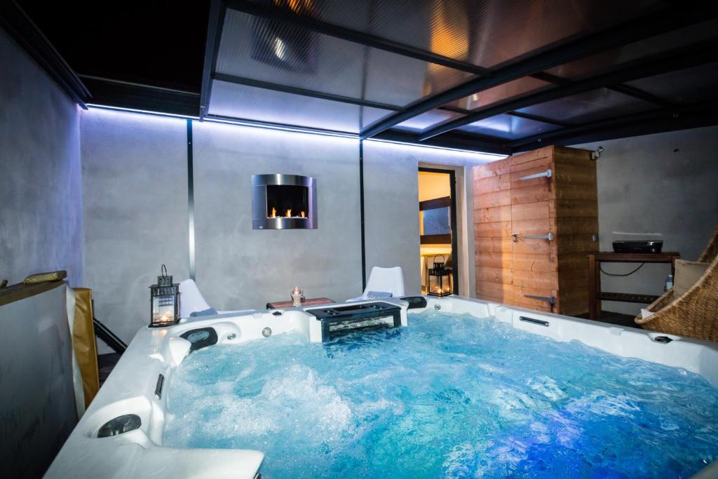 uma casa de banho com uma banheira cheia de água azul em Chambres d'hotes Deluxe Jacuzzi Mas de l'Etoile em Aigues-Mortes