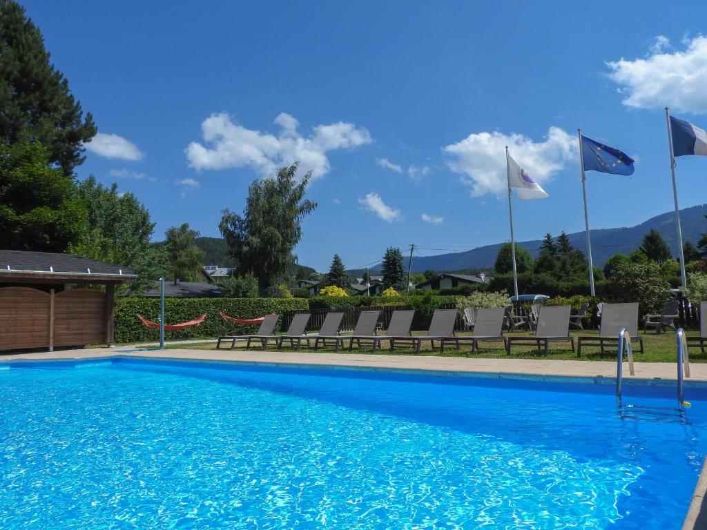 una piscina con sillas y banderas en un complejo en Logis Le Vernay en Autrans