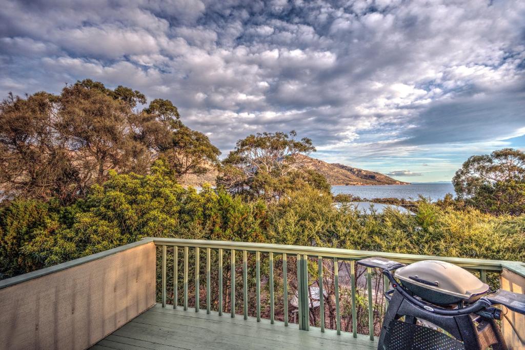 a motorcycle parked on a deck with a view of the water at Beachcroft in Coles Bay