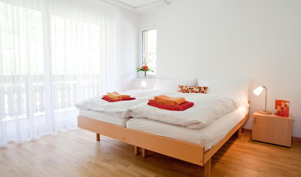 a white bedroom with a large bed with white sheets at Residence Golf C 21 in Leukerbad