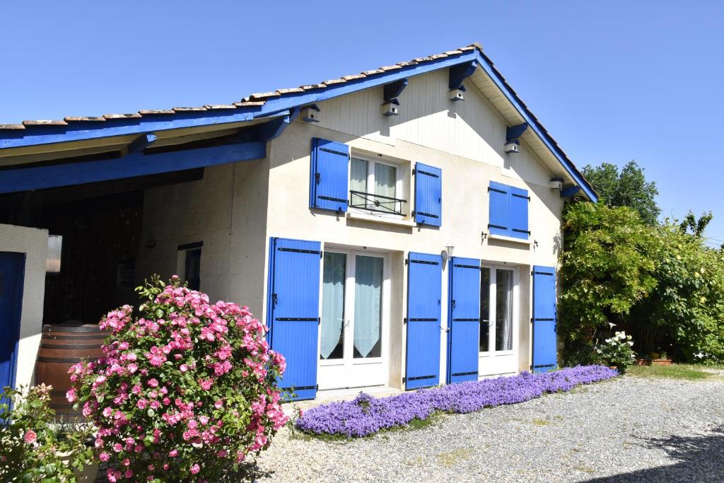 uma casa com janelas azuis e flores roxas em Maison dans le vignoble de Bordeaux-Blaye-Bourg-CNPE em Saint-Trojan