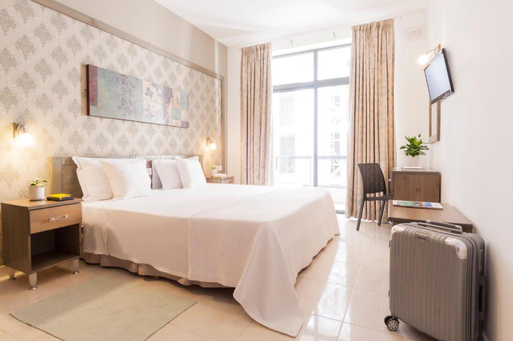 a hotel room with a bed and a suitcase at ROOMS by Alexandra Hotel in St. Julianʼs