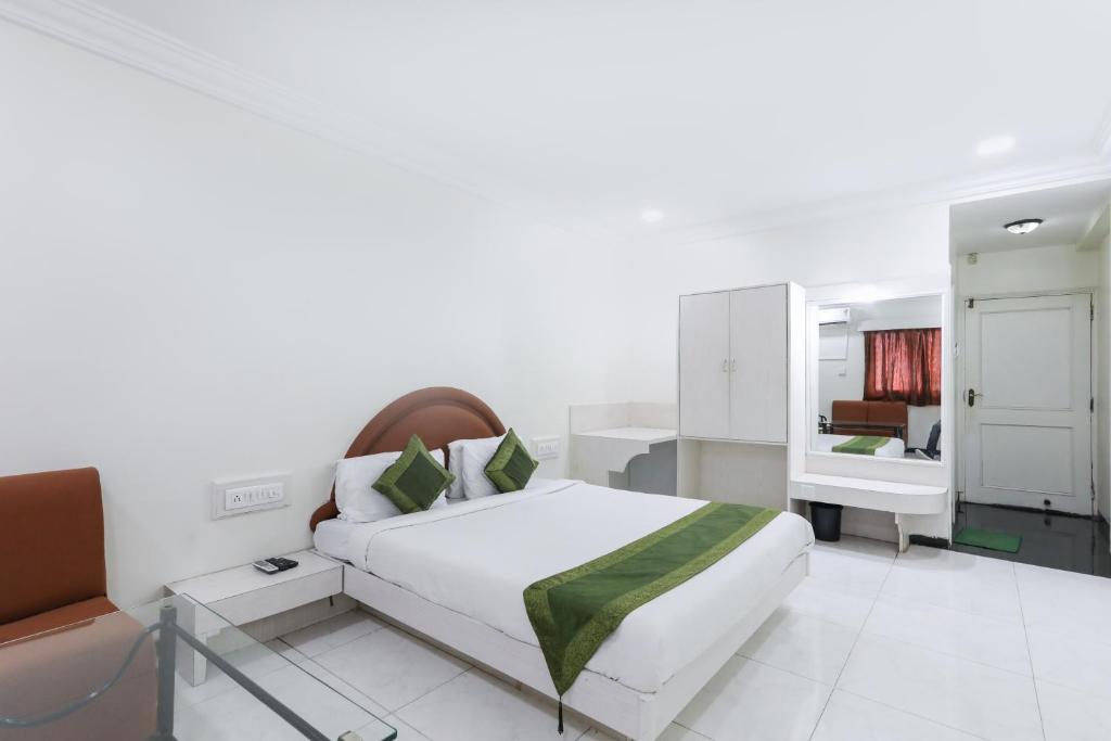 ein weißes Schlafzimmer mit einem Bett und einem Spiegel in der Unterkunft Treebo Trend Omni Palace in Indore