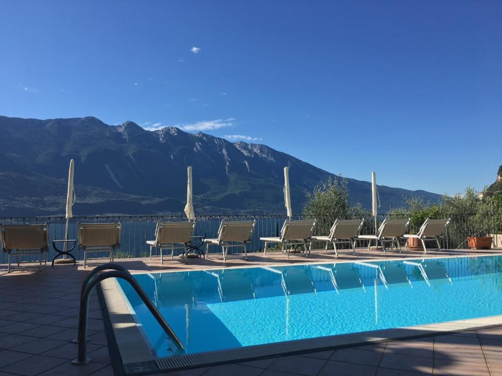 a swimming pool with chairs and mountains in the background at Villa Belvedere Hotel in Limone sul Garda