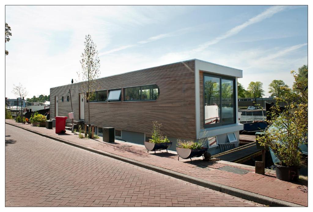 una pequeña casa en una calle de ladrillo con plantas en Private guesthouse BnB The Waterhouse houseboat, en Ámsterdam