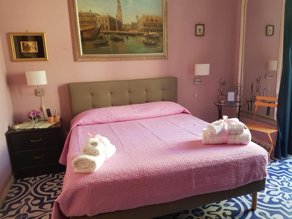 una camera da letto con un letto rosa e asciugamani di B&B Villa Italia a Salerno