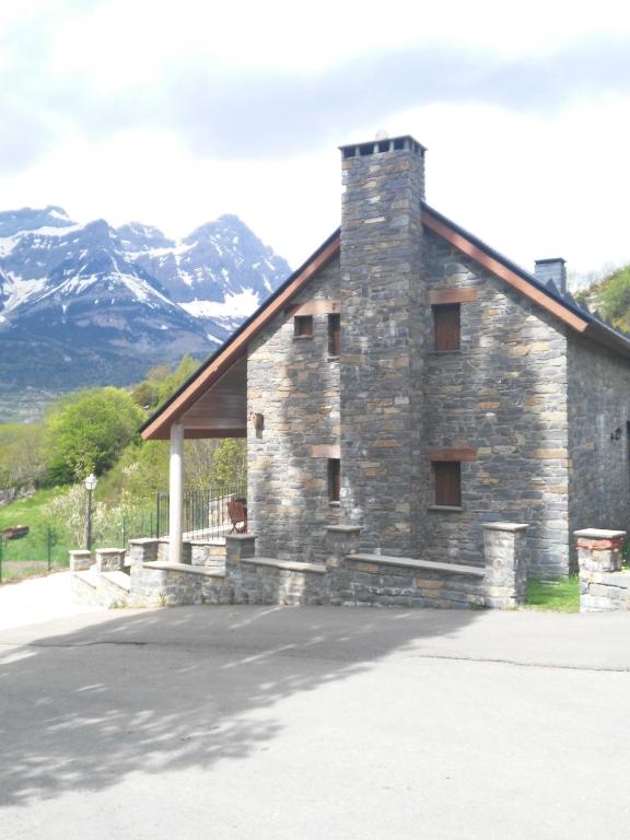 a stone building with mountains in the background at Hoz de Jaca, Casa Mas Mañanas. in Hoz de Jaca