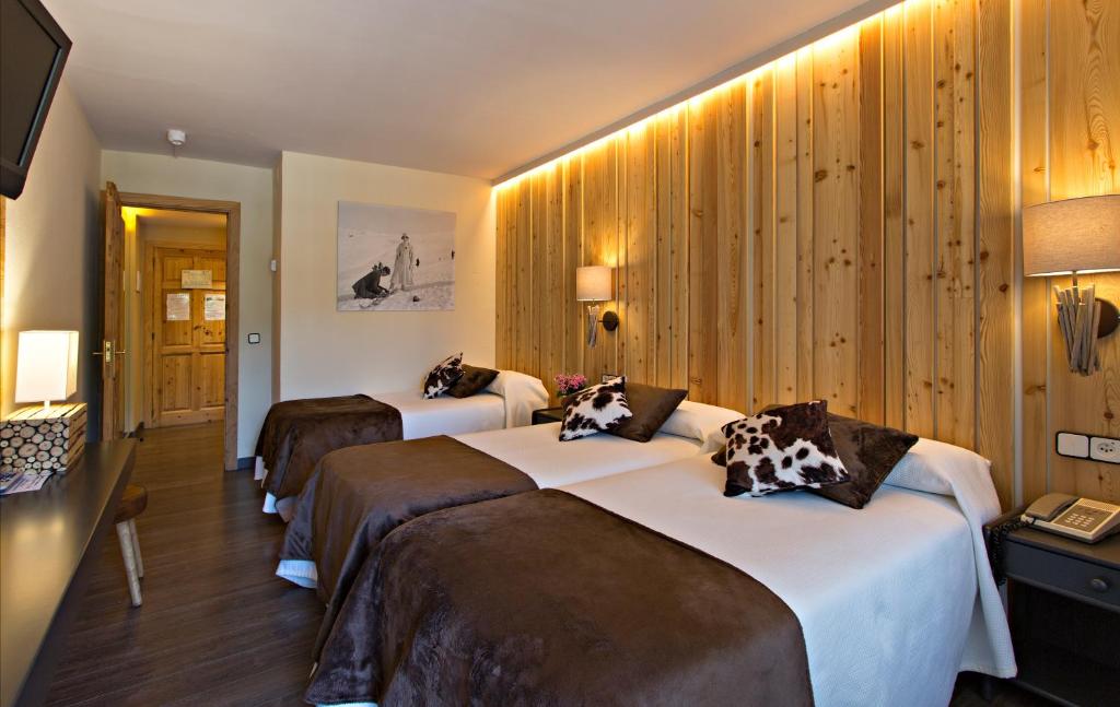 two beds in a hotel room with wooden walls at Hotel La Coma in Setcases