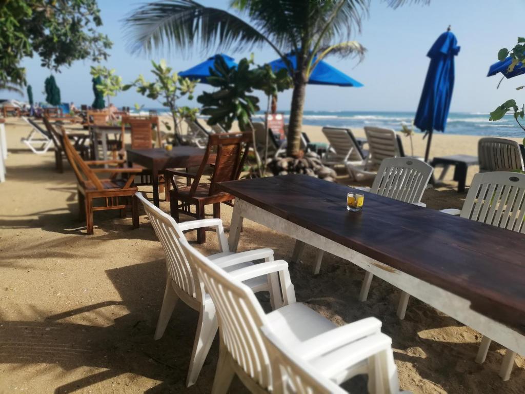 drewniany stół i krzesła na plaży w obiekcie Sunset Colony Beach Resort w mieście Galle
