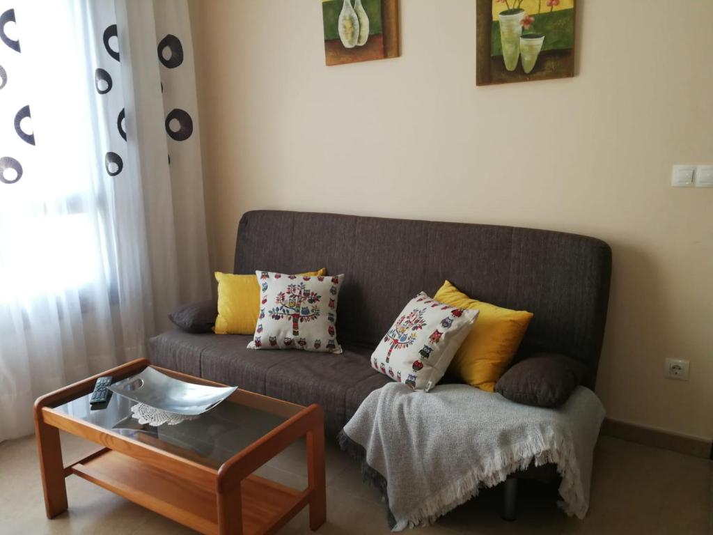 a living room with a couch with pillows and a table at Apartamentos Colmado in Sanxenxo