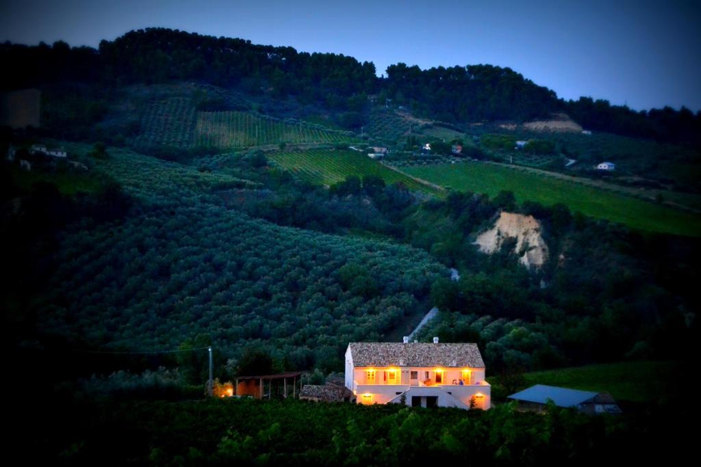 una casa in mezzo a una collina di notte di B&B Casale Fonte Vecchia a Monteprandone