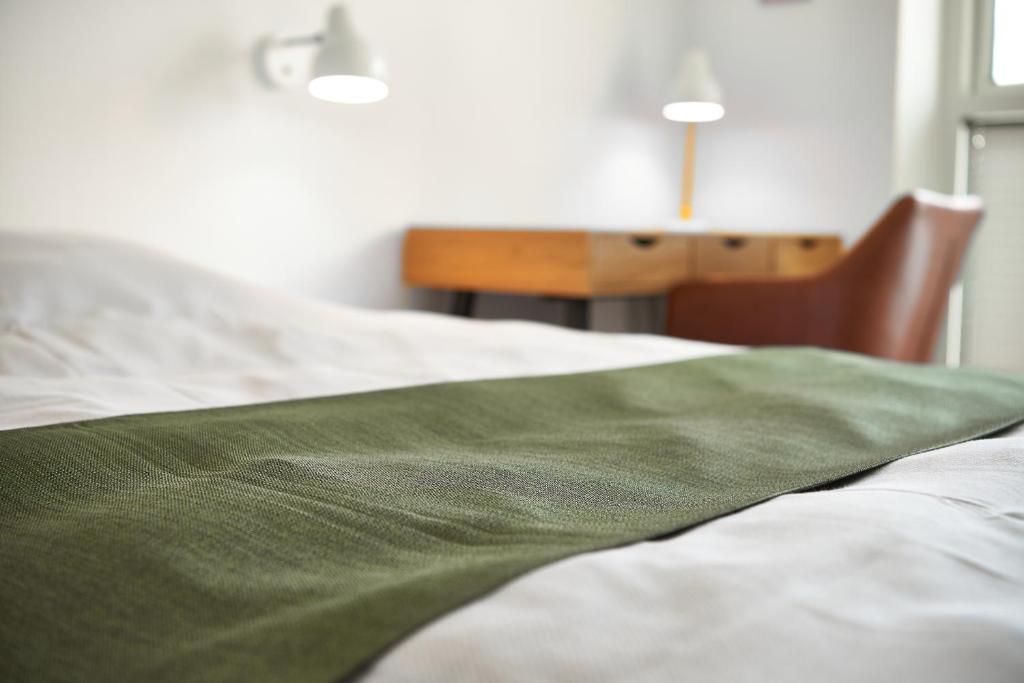 a bed with a green blanket on top of it at Hotel Phønix in Holstebro