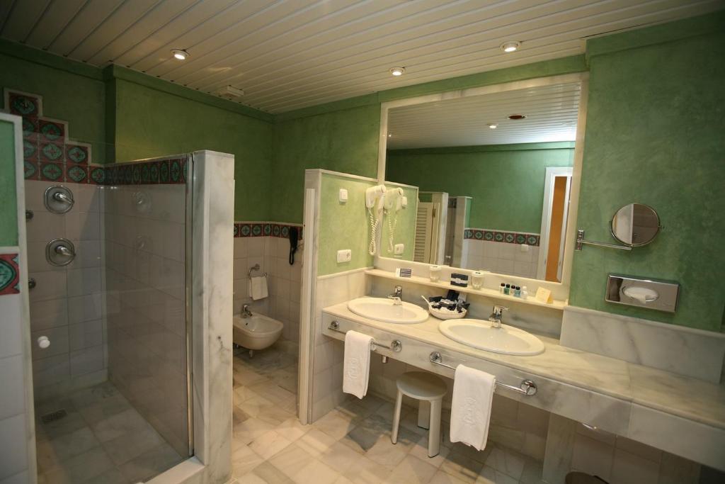 a green bathroom with two sinks and a shower at Hotel Jerez &amp; Spa in Jerez de la Frontera