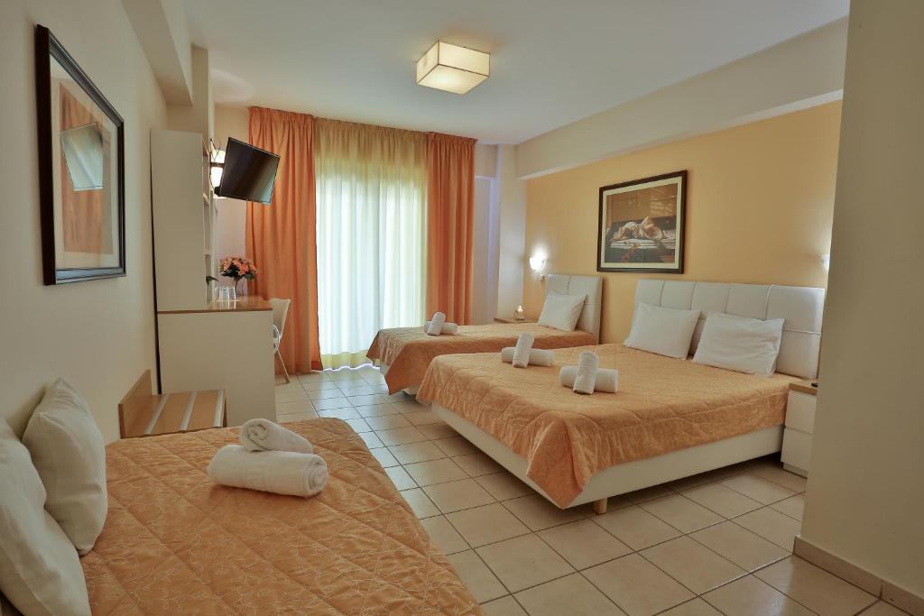 a hotel room with two beds and a couch at Hotel Ilion in Paralia Katerinis