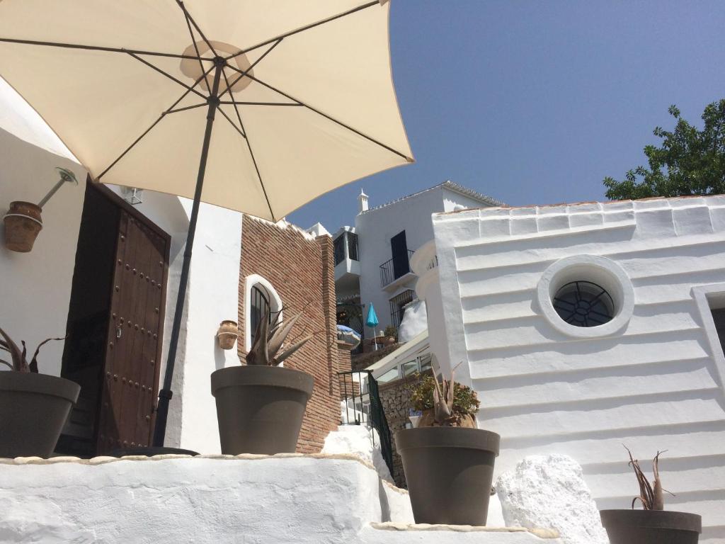 a white building with an umbrella and potted plants at La Casa Turquesa-Original in Frigiliana