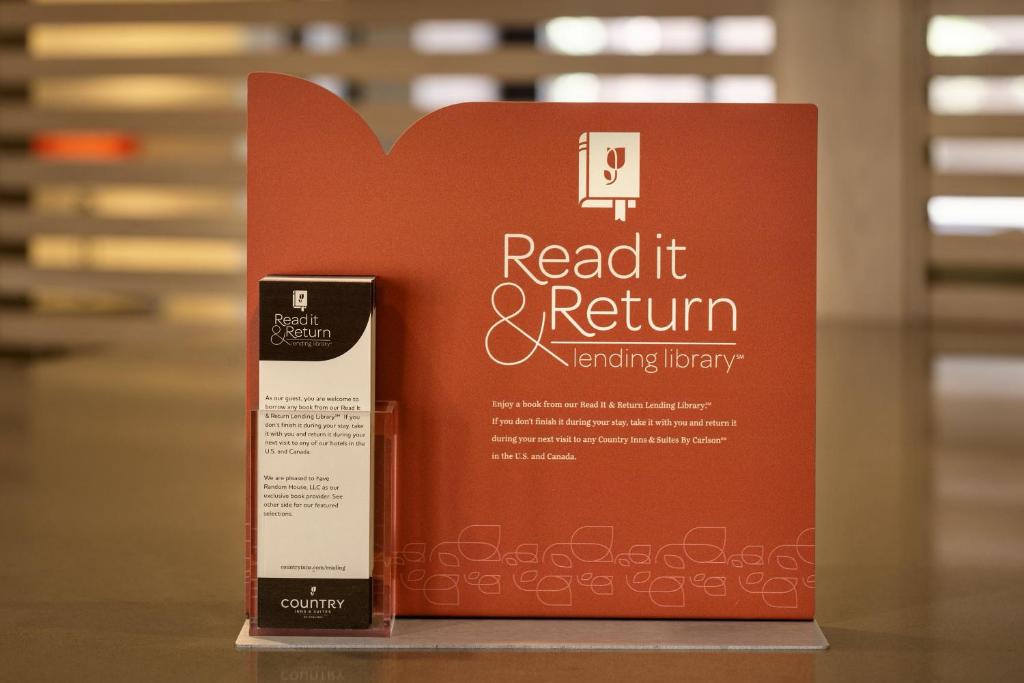 a red book sitting on a table with a cell phone at Country Inn & Suites by Radisson, Pensacola West, FL in Pensacola