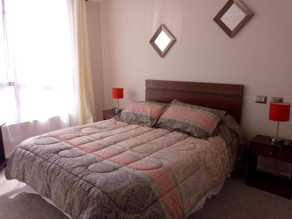 a bedroom with a bed and two lamps and a window at Departamento 706 5 Poniente in Viña del Mar