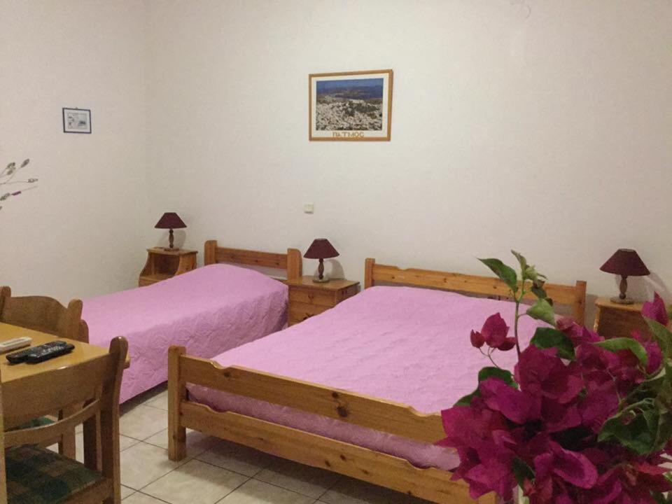 a bedroom with two beds with pink sheets and flowers at Studios Irene in Skala