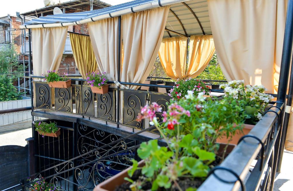 un balcón con un montón de plantas y cortinas en Bibi en Kutaisi