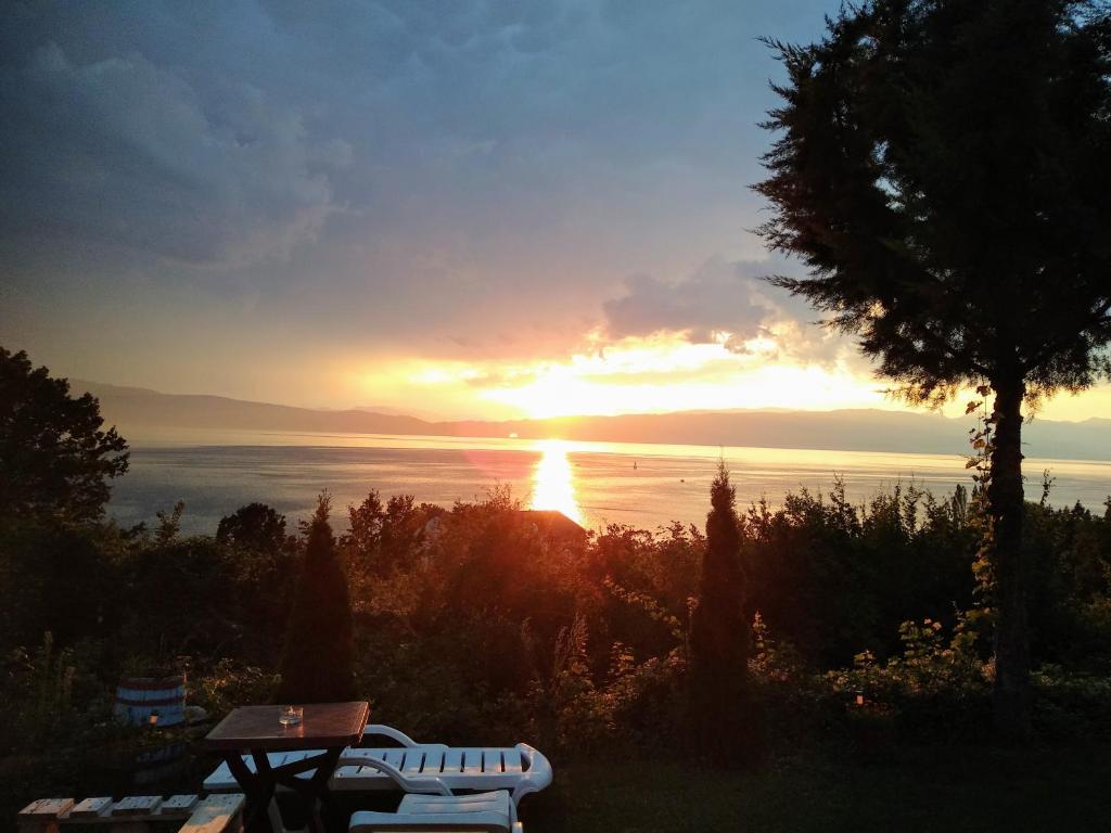 a sunset over the ocean with a table and a bench at Villa Two Brothers in Ohrid
