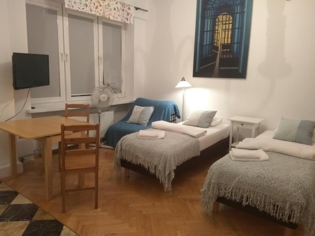 Cette chambre comprend deux lits, une table et un bureau. dans l'établissement Studio Iwicka, à Varsovie