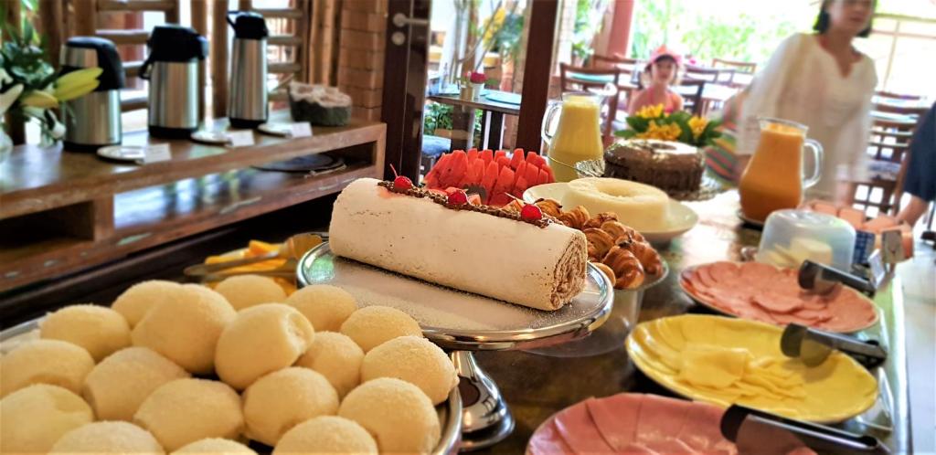a table topped with a cake and plates of food at Pousada João Sol in Praia do Forte