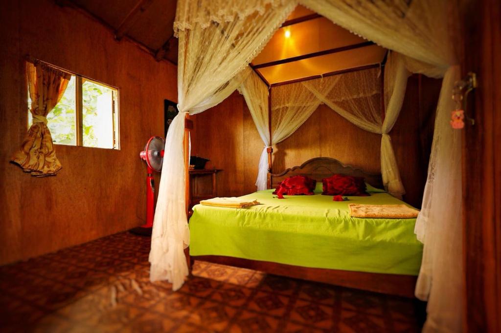 a bedroom with a green bed with a canopy at Sigiri Aliya Tree house in Sigiriya