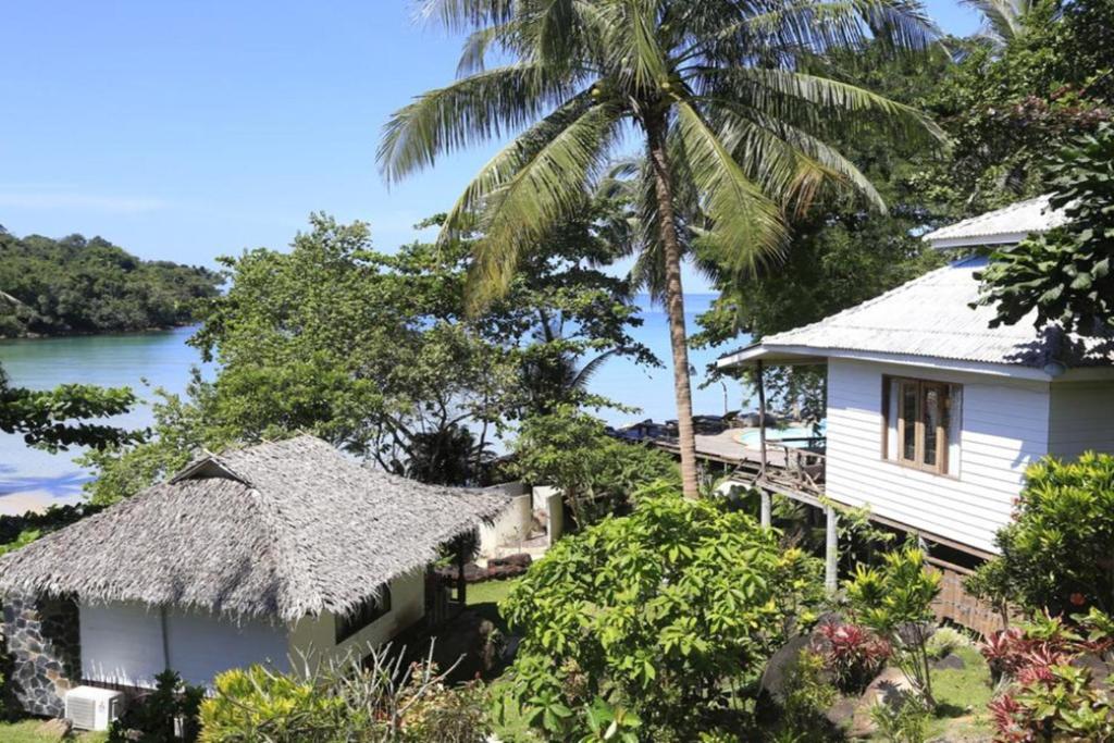 ein weißes Haus mit einem Strohdach und einer Palme in der Unterkunft A-Na-Lay Resort Koh Kood in Ko Kood