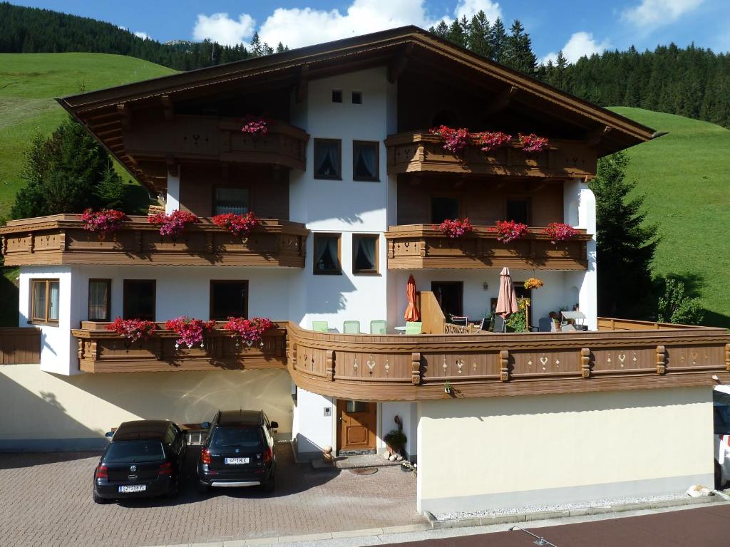 two cars parked in front of a building with balconies at Haus Dristner in Tux