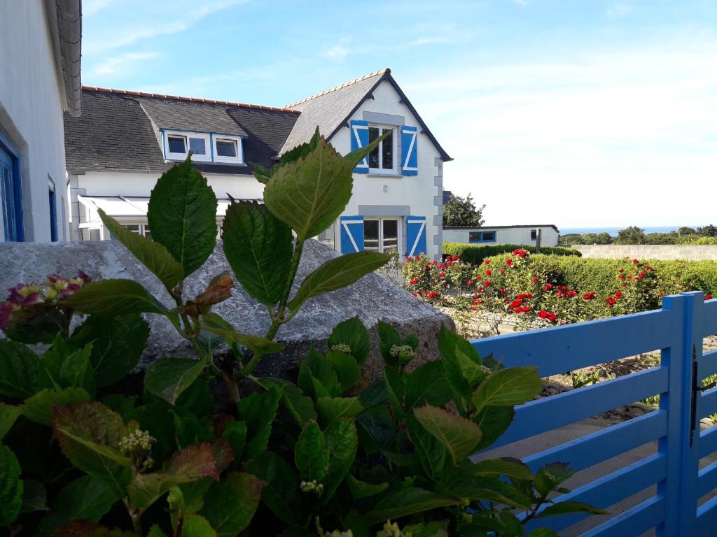 a house with a blue fence and a plant at Maison de bord de mer à Keriec in Trélévern