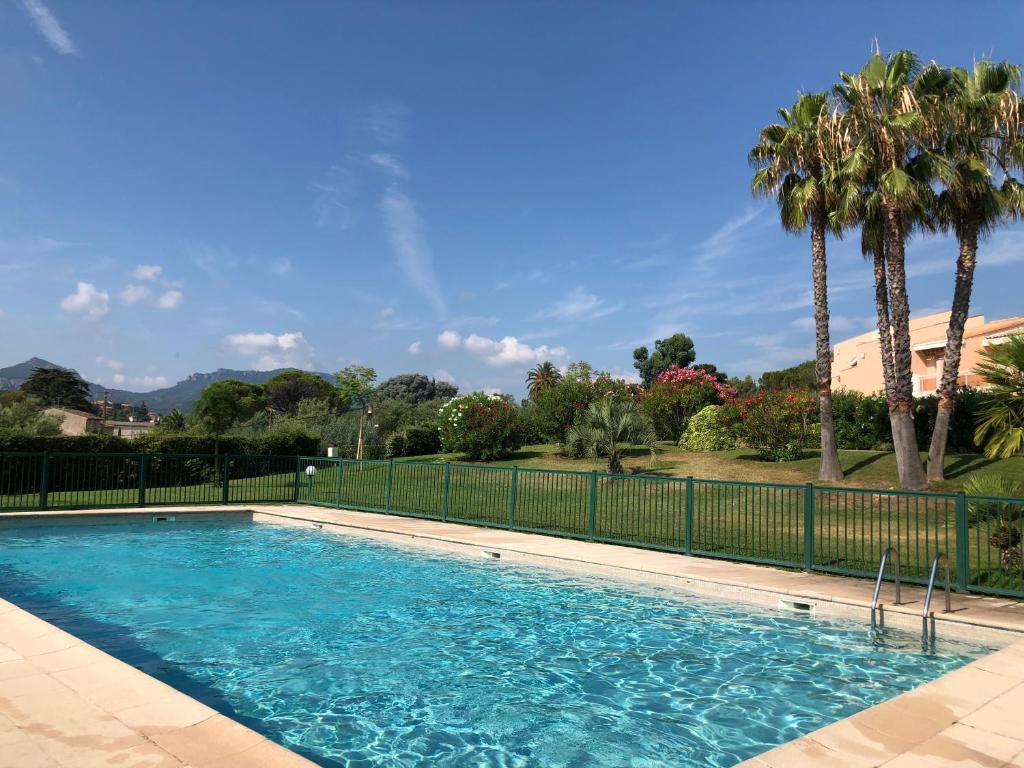 une piscine avec une clôture et des palmiers dans l'établissement Appt T2 refait à neuf - vue mer dans résidence avec piscine, à Mandelieu-la-Napoule