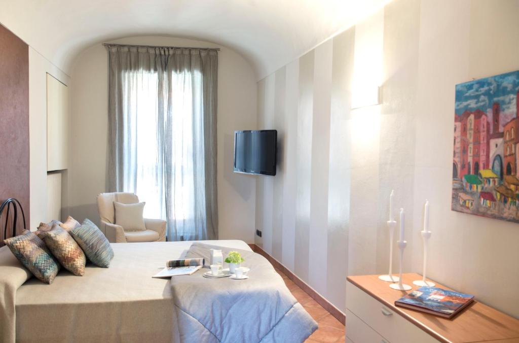 um quarto com uma cama, um sofá e uma televisão em La Finestra sul Borgo em Alba