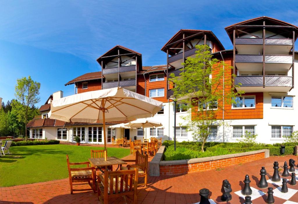 un edificio con mesa, sillas y sombrilla en relexa hotel Harz-Wald Braunlage GmbH en Braunlage