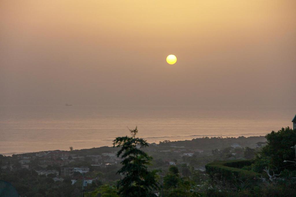 a sunset over the ocean with the sun in the sky at Sunshine Lodge: Your home away from home in Montego Bay
