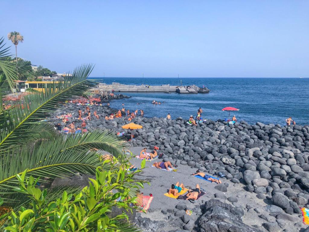 a group of people laying on a rocky beach at La Casa Di Iside A Mare in Catania