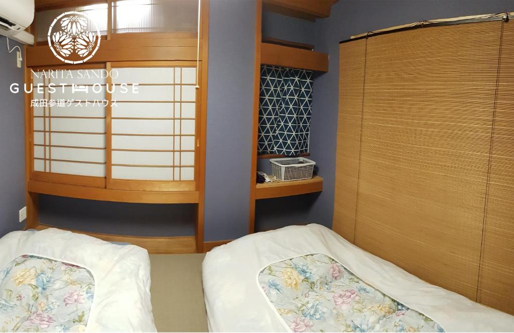 a bedroom with a bed and a wooden cabinet at Narita Sando Guesthouse in Narita
