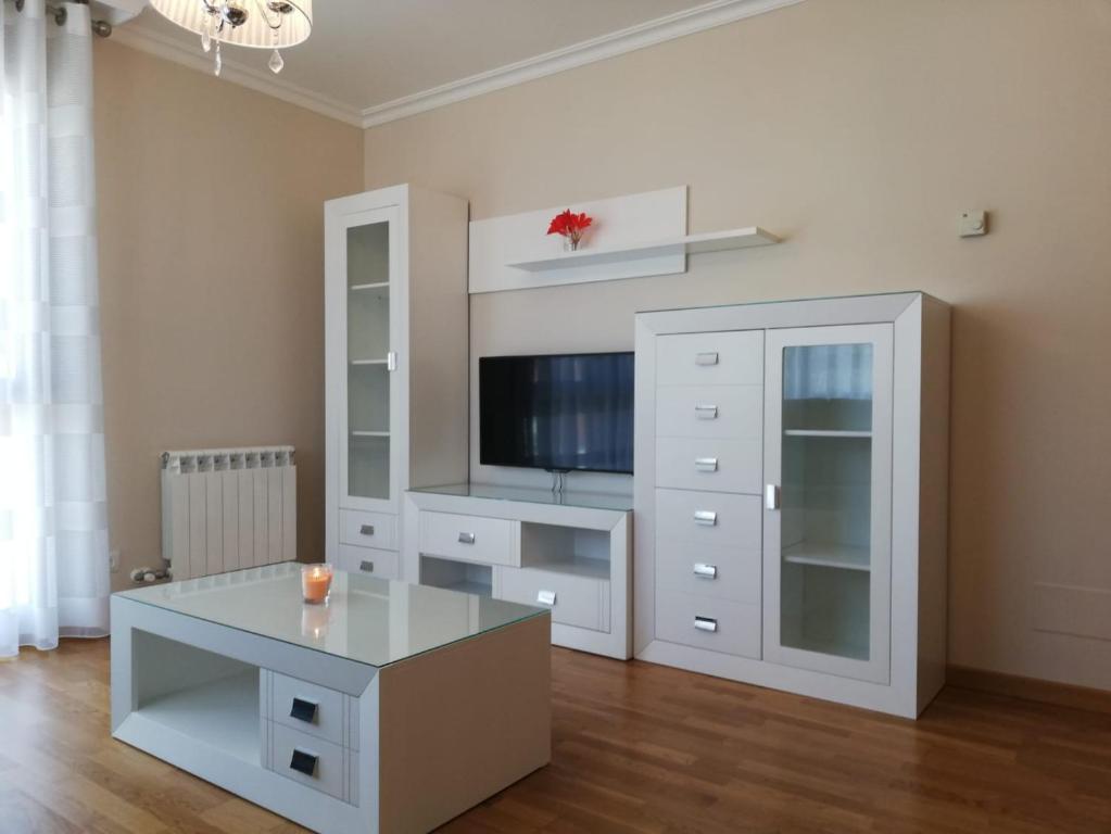 uma sala de estar com uma televisão e um armário branco em Pedrouzo Suites em O Pedrouzo