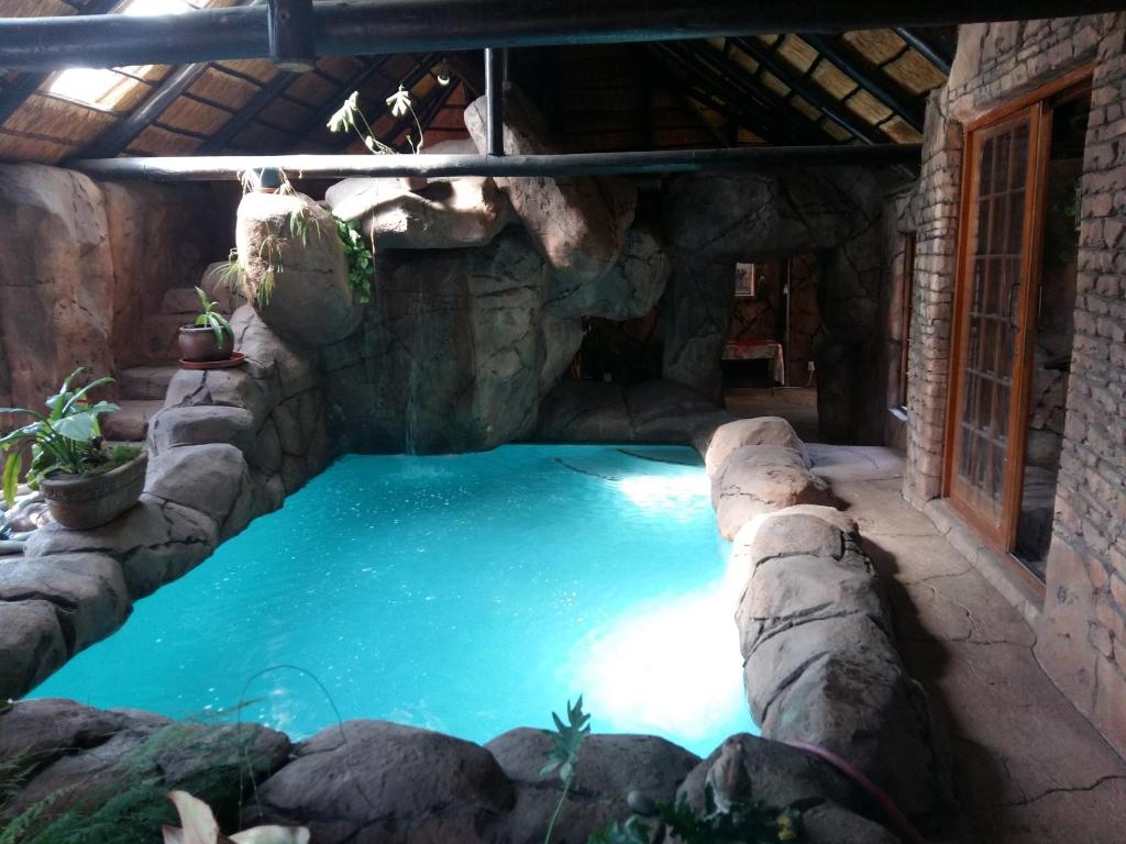 einen Pool in einer Höhle mit einer Steinmauer in der Unterkunft Pride Rock Accommodation in Middelburg