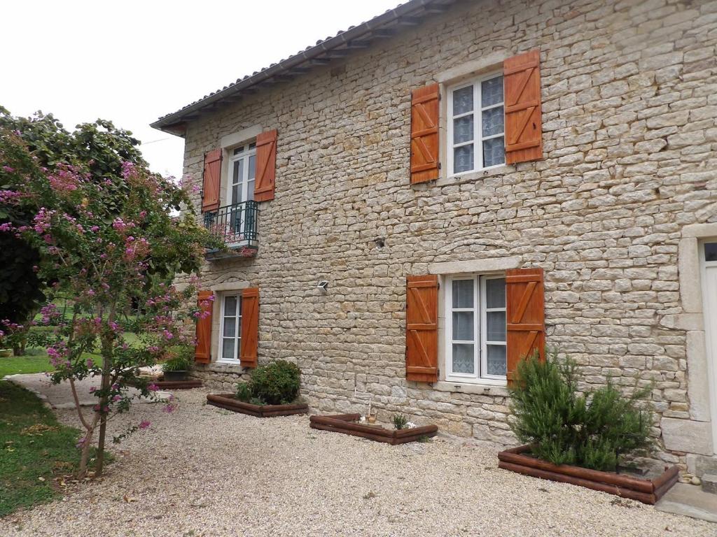 a stone house with wooden shuttered windows and a yard at Litdevin in Uchizy