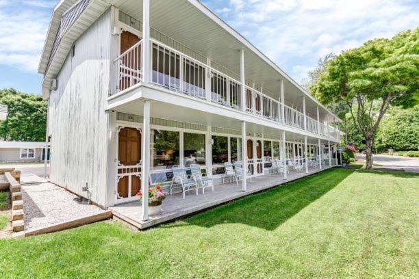 een groot wit huis met tafels en stoelen op het gazon bij Fish Creek Inn in Fish Creek