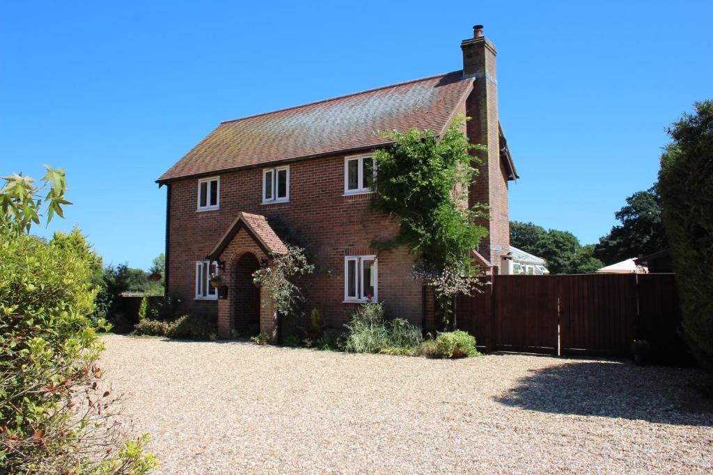 una vecchia casa di mattoni rossi con una recinzione di Graceland Farm B&B a Brockenhurst