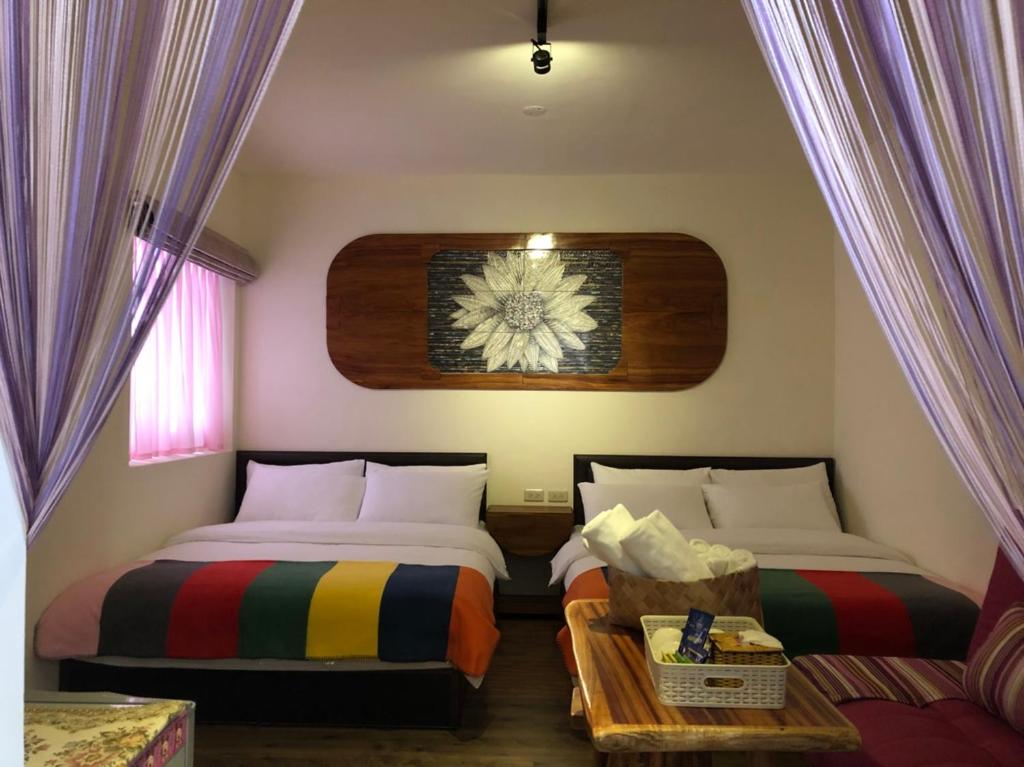 a bedroom with two beds and a table and a window at Jilufugan B&amp;B in Taimali