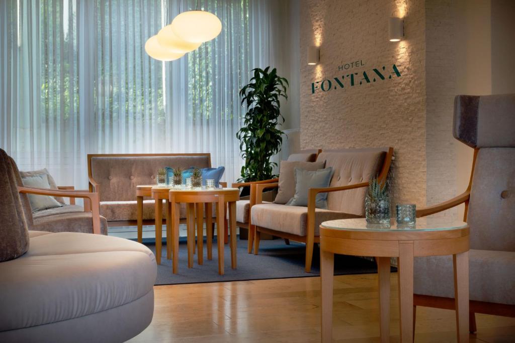 una sala d'attesa con tavoli e sedie e un cartello di Hotel Fontana a Bad Kissingen