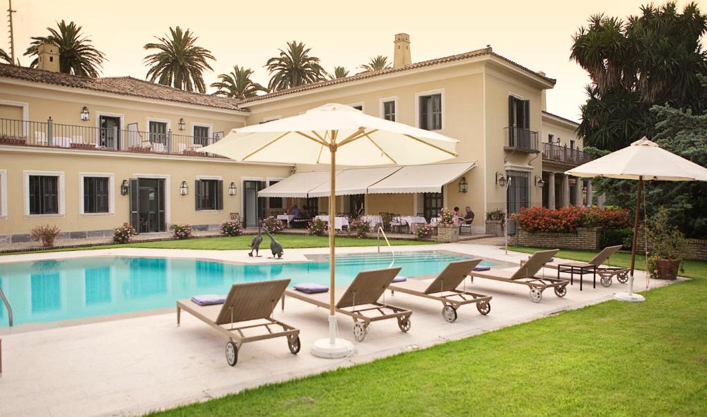 a house with a swimming pool with chairs and umbrellas at Villa Jerez in Jerez de la Frontera