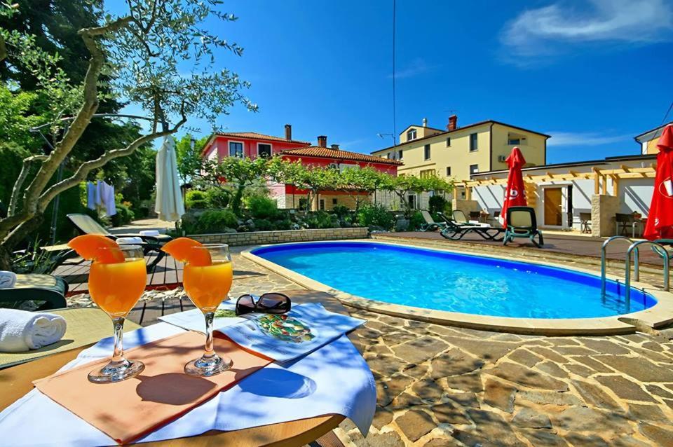 a swimming pool with a table with two glasses on it at Apartmani Elio in Umag