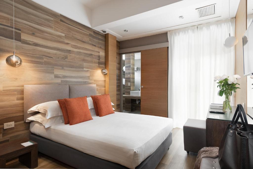 1 dormitorio con cama blanca y pared de madera en Bio Boutique Hotel XU' - Gruppo Ambienthotels, en Rímini