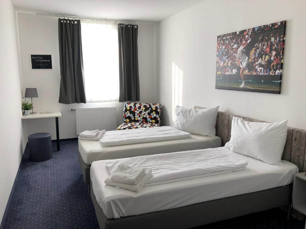 a hotel room with two beds and a window at Pension Tennisweber in Schwechat