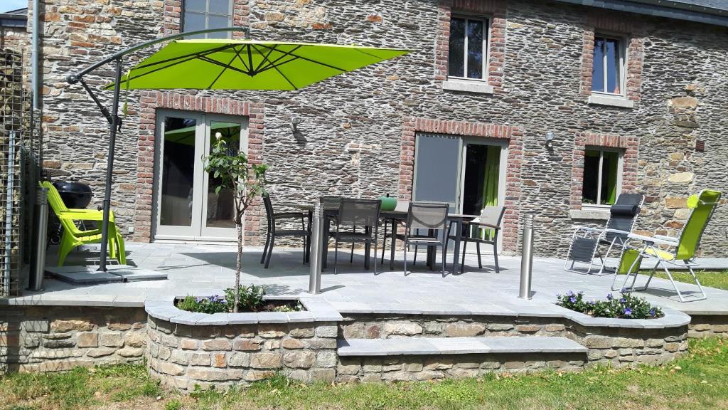 une terrasse avec une table, des chaises et un parasol dans l'établissement Gîte Au Coeur de Champlon, à Champlon