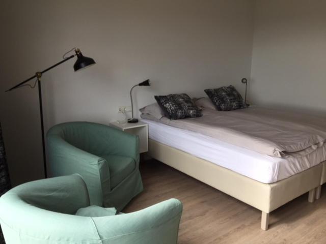 a bedroom with a bed and a chair and a lamp at Apartment Brekka í Lóni in Stafafell